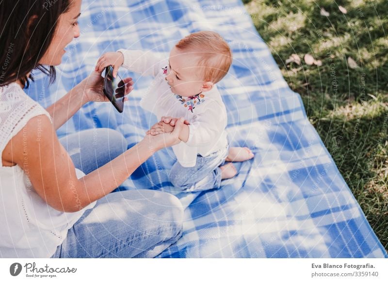 young mother and happy baby using mobile phone outdoors. technology concept Mother Baby Cellphone Technology Together Child Parenting Girl Joy Sunbeam Parents