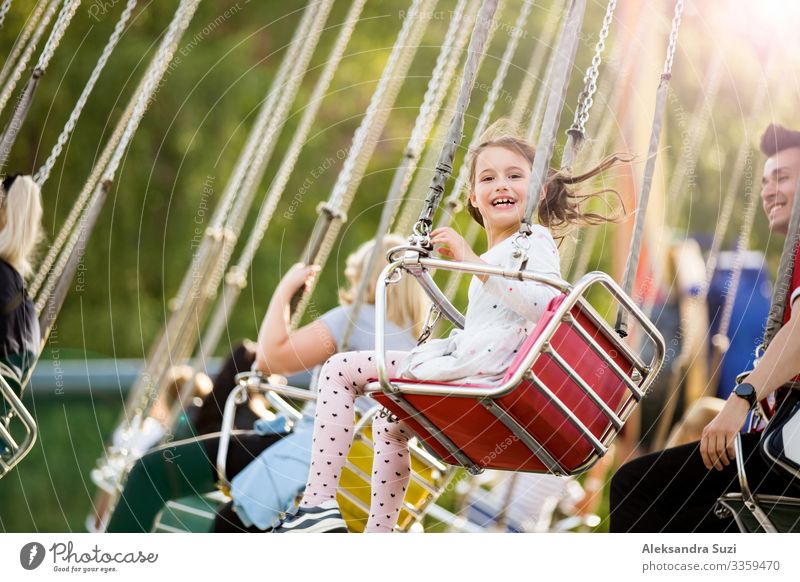 Little girl having fun on chain carousel. Happy summer memories. Carefree childhood and happiness action activity adventure amusement beautiful cheerful circle