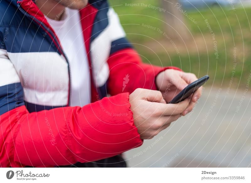 Young man with smartphone in hand texting outdoors in the street mobile holding using technology mobile phone device message cyberspace digital male person