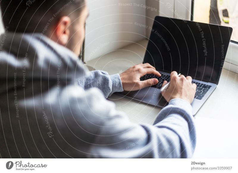 Rear view of a young man working with laptop on desktop Decoration Desk Table Work and employment Workplace Office Business Computer Notebook Screen Software