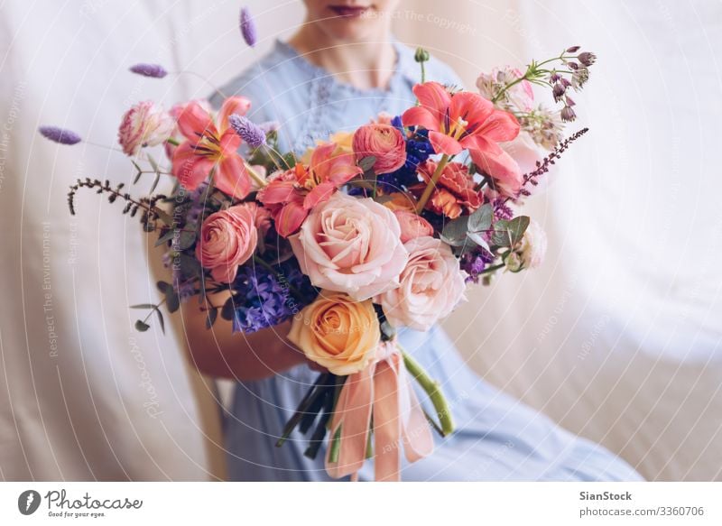 Young woman in a light blue dress holding a bouquet of flowers. Lifestyle Elegant Style Happy Beautiful Chair Wedding Woman Adults Lips Hand Flower Dress