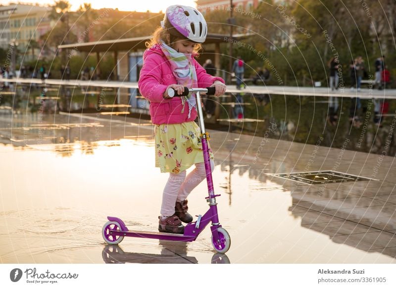 Cute kid in helmet riding scooter on city square. Action candid Child Infancy City France Joy Girl Happy Helmet Leisure and hobbies Lifestyle Movement Nice