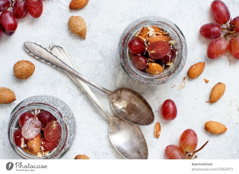 Chia pudding parfait with red grapes and almonds Yoghurt Fruit Dessert Eating Breakfast Diet Spoon White jar chia Bunch of grapes nuts Pudding seed chia seeds