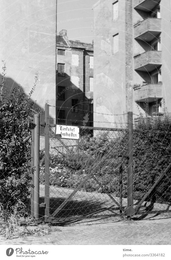 Stories from the Fence (101) Highway ramp (entrance) sign keep Goal houses skyscrapers Backyard locked Hedge shrubby Facade Wall (barrier) sunny Shadow