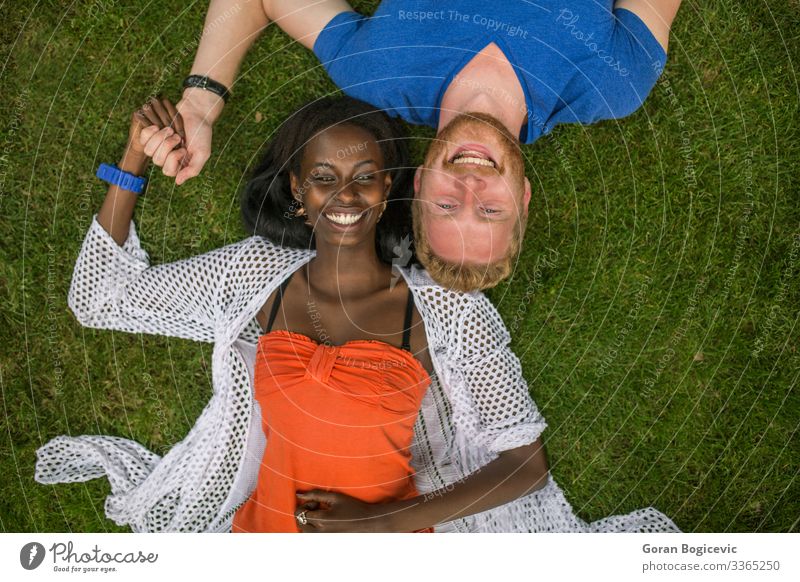 Multiracial couple in the park Lifestyle Summer Human being Young woman Youth (Young adults) Young man Woman Adults Man Couple 2 18 - 30 years Grass Red-haired