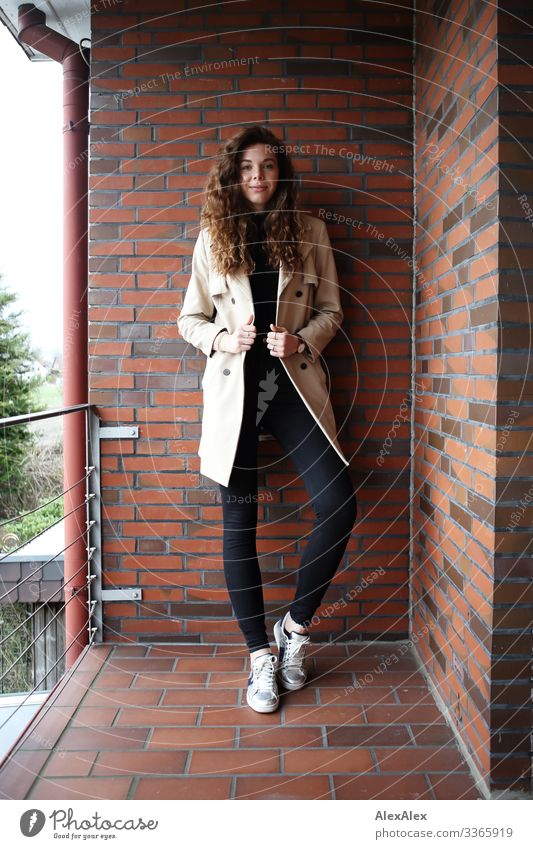 Young, tall woman standing on a balcony with a brick wall Lifestyle Style Joy already Living or residing Balcony Young woman Youth (Young adults) 18 - 30 years