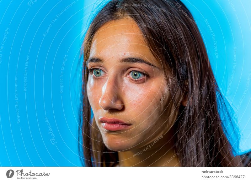 Face of Beautiful Olive Skinned Woman with Light Colored Eyes on Blue Background female girl woman young adult light colored eyes eye color female beauty