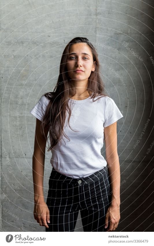 Young Woman in Front of Concrete Wall Indoors female girl woman young adult portrait serious looking at camera medium shot beautiful woman natural beauty