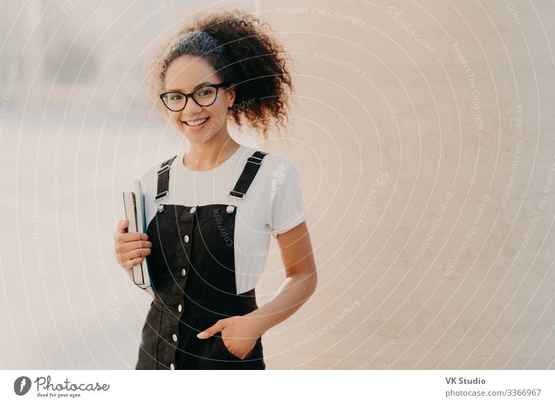 Lovely curly woman with combed hair, keeps hand in pocket Style Happy Study Academic studies Work and employment Human being Woman Adults 1 18 - 30 years