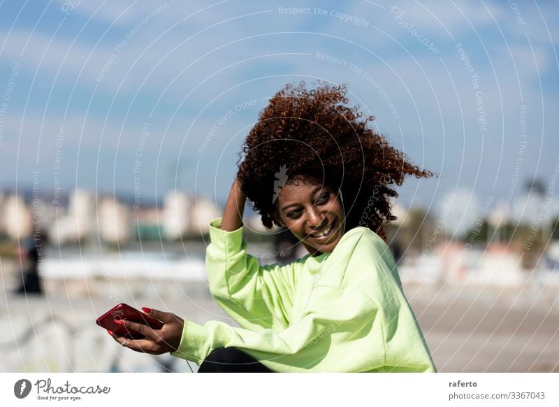 Beautiful afro woman sitting on shore using a mobile phone Style Happy Beach Telephone PDA Human being Feminine Young woman Youth (Young adults) Woman Adults 1