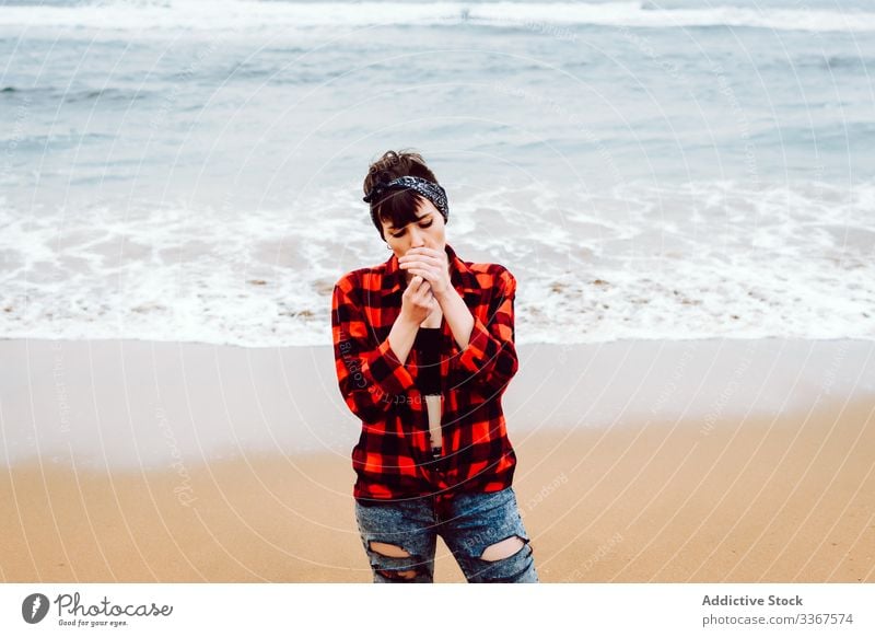 Woman lighting cigarette on beach woman smoke casual sea serious concept stormy sand young female ocean water red nature travel coast seaside environment lonely