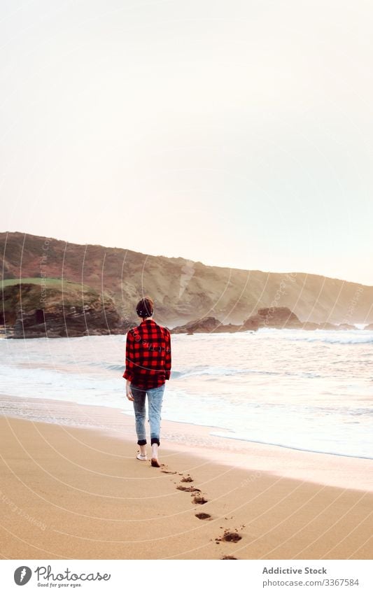 Woman walking on wet sand on beach woman footprint concept sea barefoot ocean female water nature travel coast seaside environment lonely overcast cloudy waves