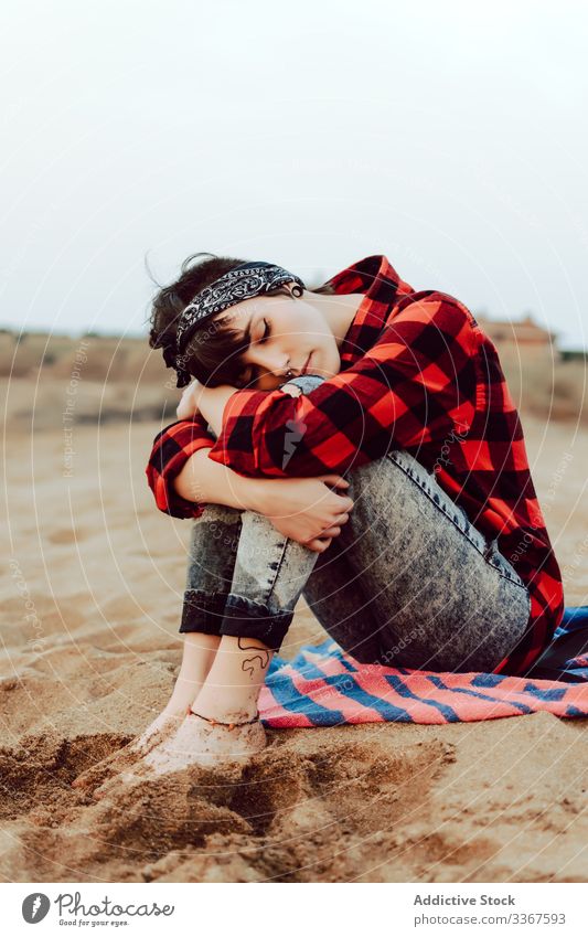 Thoughtful hipster woman sitting on sandy beach pensive serious young relax thoughtful sea casual female ocean observation think red nature travel coast seaside