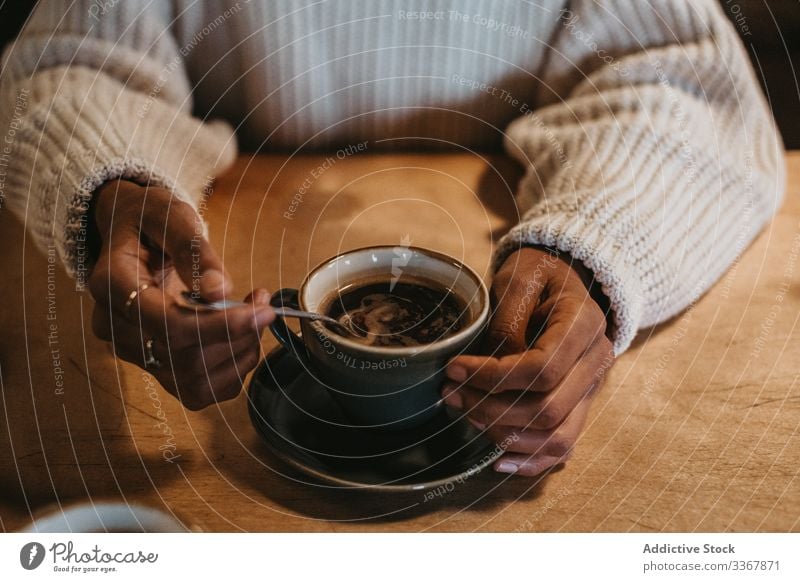 Anonymous woman with coffee cup in cafe hand adult female person sitting enjoying fresh hot brewed mug drink beverage black table wooden cafeteria indoors