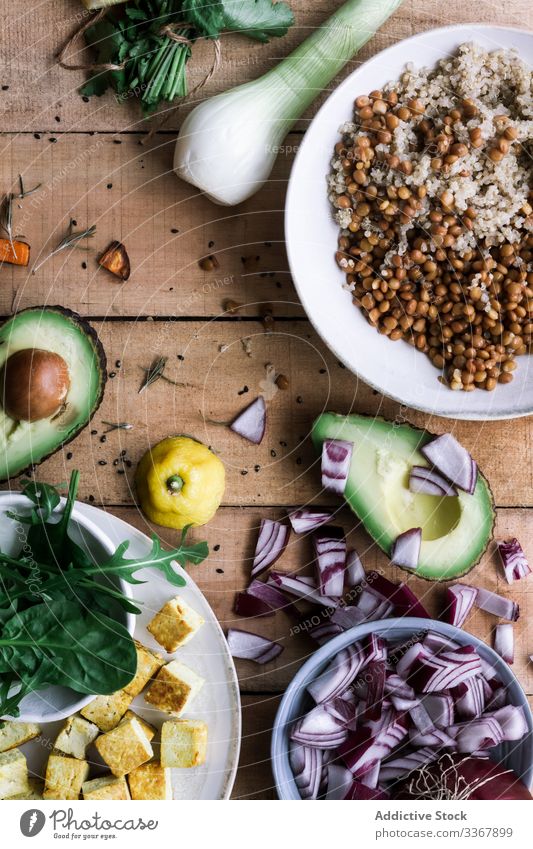 Different kind of vegetables and ingredients on rustic table cut onion avocado sweet potato process preparation greens food cook meal dinner organic vegetarian