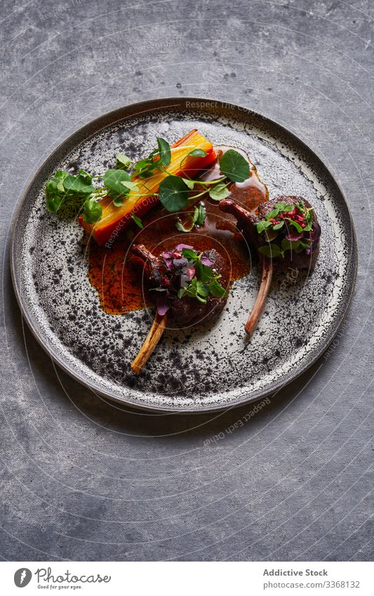 Top view of tasty meat medallions with herbs on plate sauce food meal cuisine delicious yummy dish dinner lunch gray table surface stucco plaster restaurant