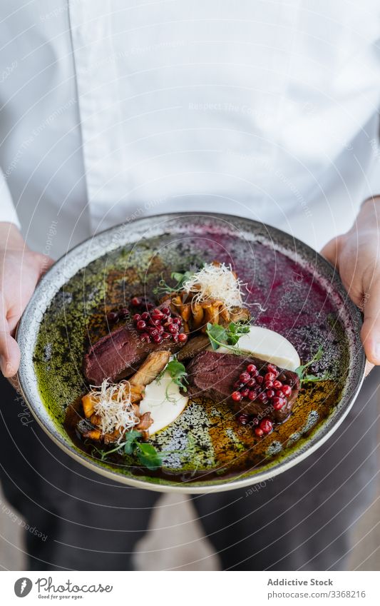 Anonymous person holding plate with rare steak with cranberry sauce sweet cheese mushroom herb meat beef food meal sliced piece exquisite served red gourmet