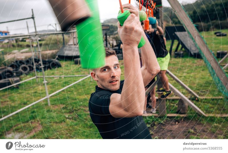 Man in obstacle course doing suspension exercises Sports Human being Woman Adults Arm Group Observe Fitness Hang Authentic Strong Power Effort Competition