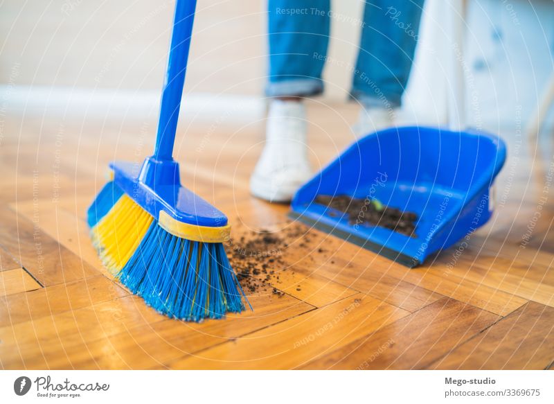 Latin man sweeping wooden floor with broom at home. housework household housekeeper object indoor equipment living concept apartment holding tidy tool closeup