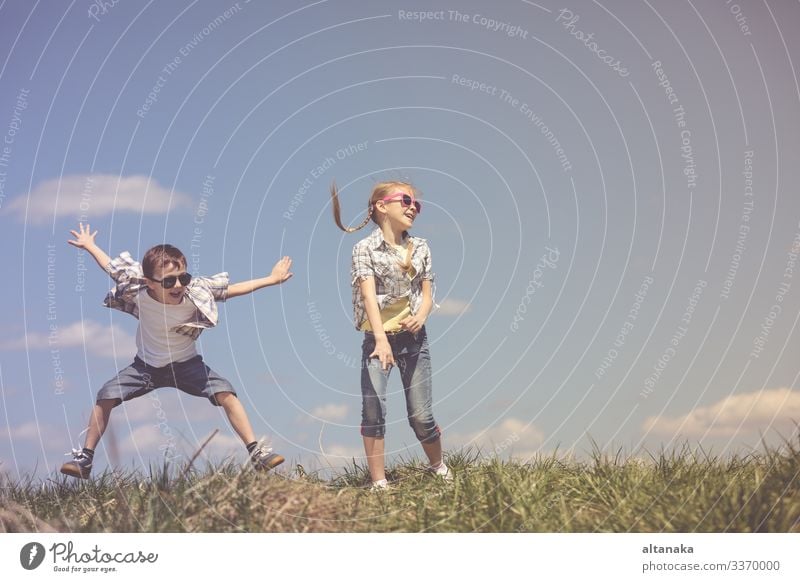 Brother and sister playing on the field at the day time. Children having fun outdoors. They running on the lawn. Concept of friendly family. Lifestyle Joy Happy