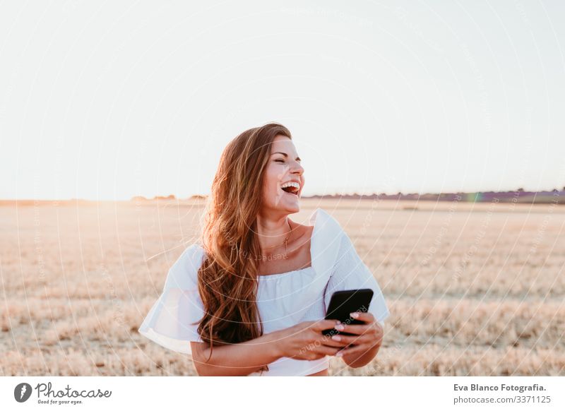 young beautiful woman on countryside at sunset using mobile phone. technology concept portrait outdoors caucasian summer lifestyle happiness smile adult nice