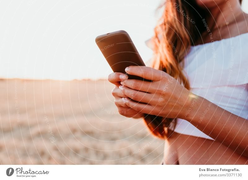 unrecognizable young beautiful woman on countryside at sunset using mobile phone. technology concept portrait outdoors caucasian summer lifestyle happiness