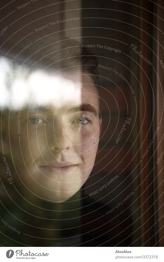 Portrait of a young man behind the window pane with reflections Style pretty Contentment Flat (apartment) Room Window Young man Youth (Young adults) Face