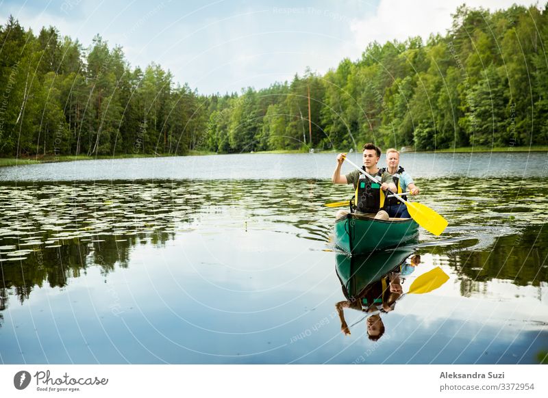 Two men in life vests canoeing in forest lake. Action Adventure candid Canoe Destination Discover Finland Forest Happy Lake Landscape Lifestyle Man Nature