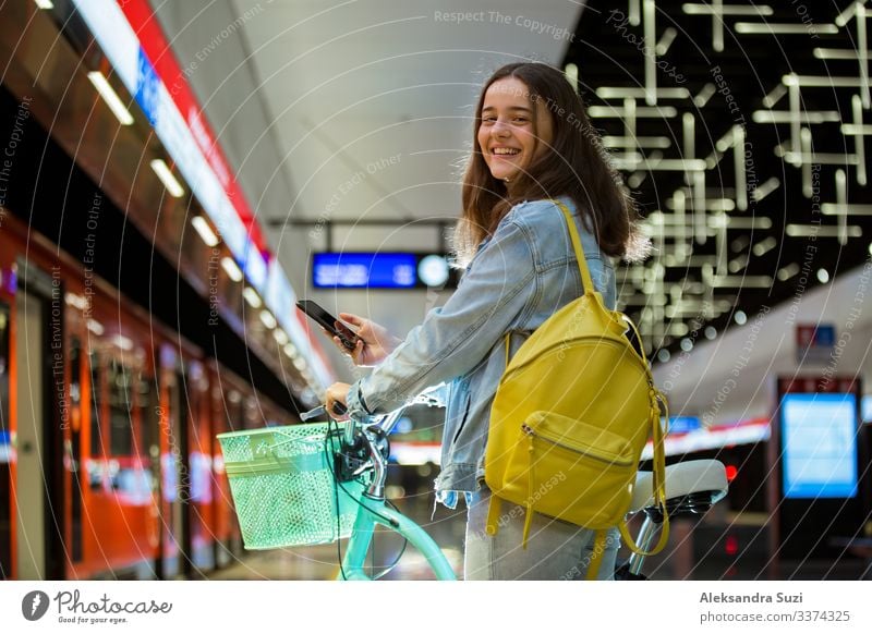 Teenager girl with backpack and bike on metro station Action Bicycle Cycling Easygoing Casual clothes Friendliness Cheerful City Destination Ecological Finland