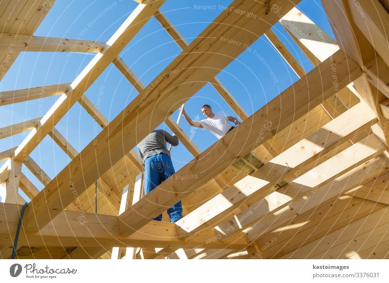 Roof builders mounting prefabricated wooden roof construction. Construction industry concept. House (Residential Structure) Work and employment Craftsperson