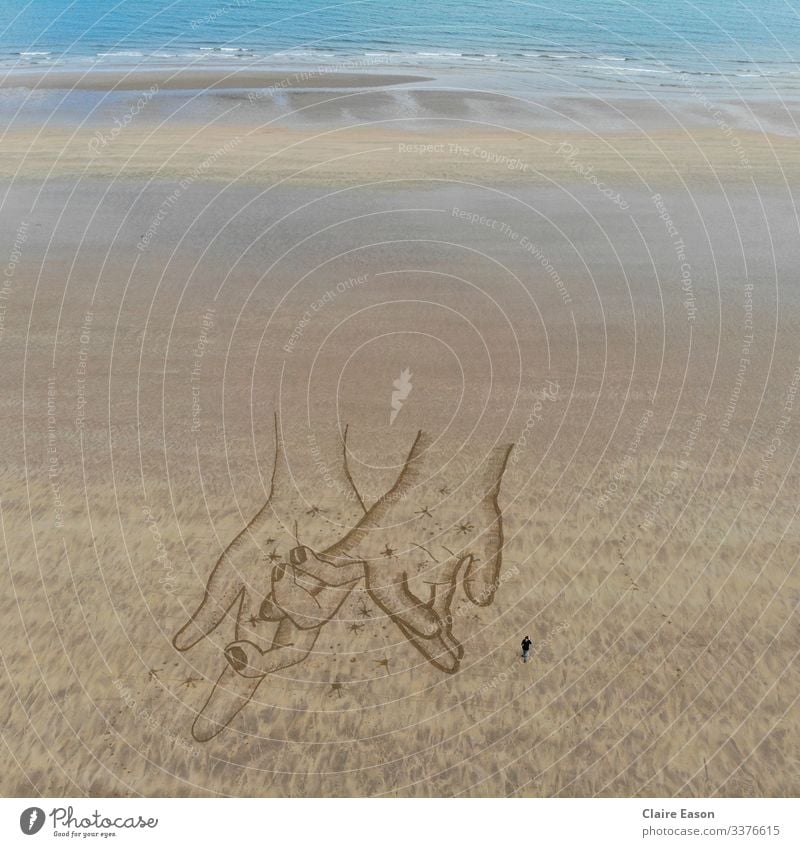 Giant sand art drawing of holding hands created by dji camera touching beach coast sustainable ecotourism environment nature Together togetherness