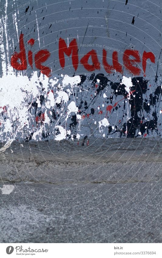 the wall is red on the concrete wall in blue with splashes of paint in front of a street, written Wall (barrier) Deserted Structures and shapes Pattern