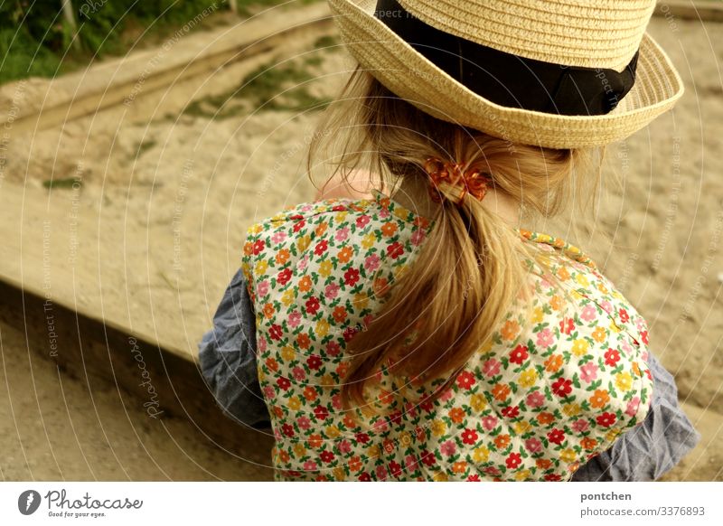 Female toddler from behind playing at the sandbox Sandpit girl Toddler Playing long hairs braid Blonde Elastic hairband Hipster Flowery pattern garments Vest