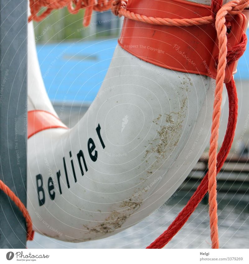 Lifebelt with the inscription Berliner hangs from a metal pole on the riverbank Life belt Ring Rescue peril Protection Rope String Help Town Capital city