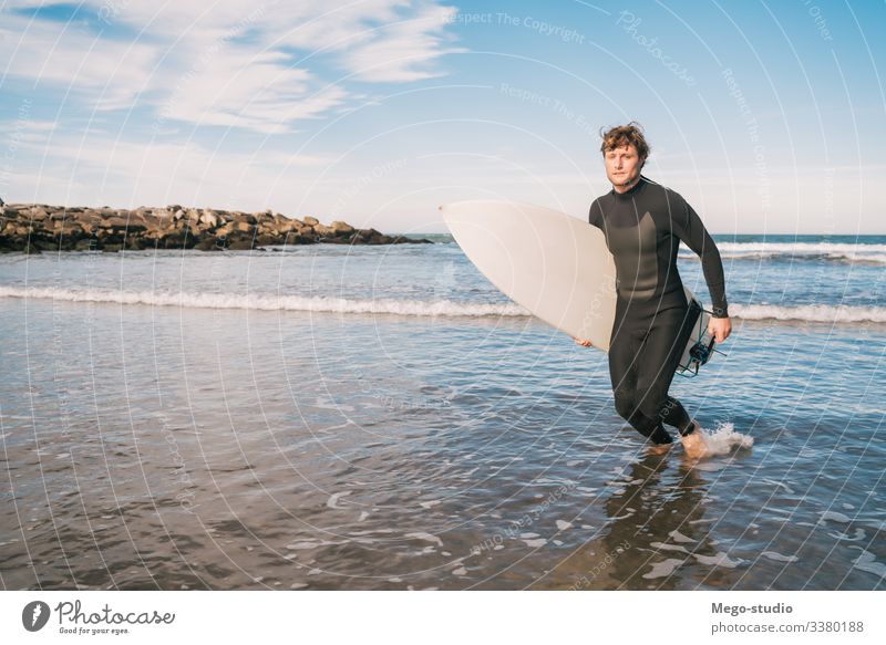 Surfer leaving the water with surfboard under his arm. man sport surfing sea surfer ocean outdoors athletic scenic coastline waves background adventure sports