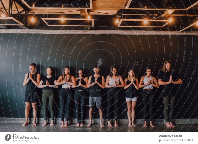 Cheerful athletes practicing yoga together in mountain pose in contemporary workout room relax meditate class namaste exercise tadasana breath happy studio