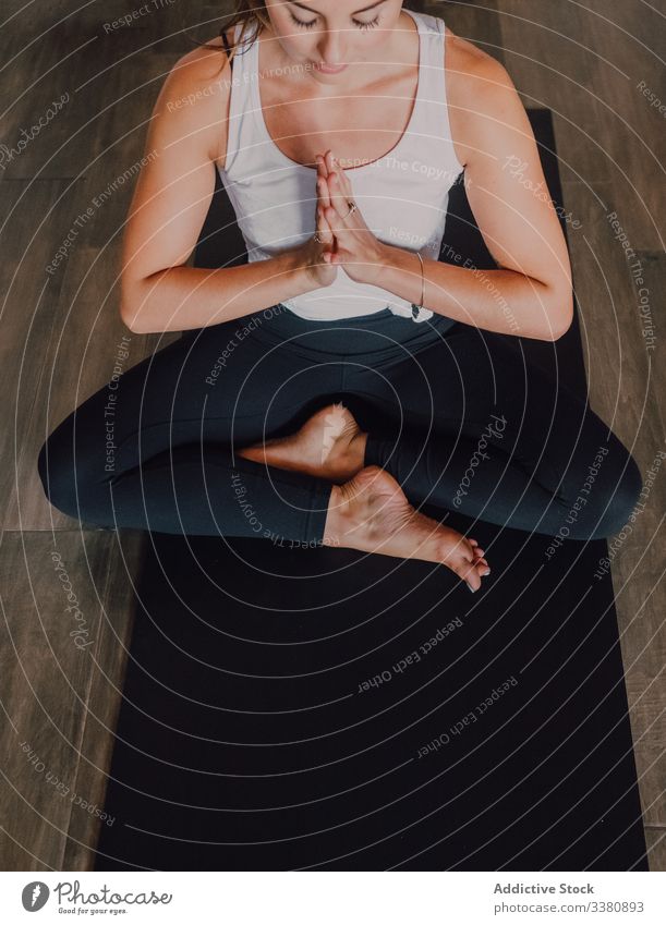 Slim barefoot woman meditating in bound angle pose in contemporary workout room meditation yoga relax practice asana namaste exercise training athletic stretch