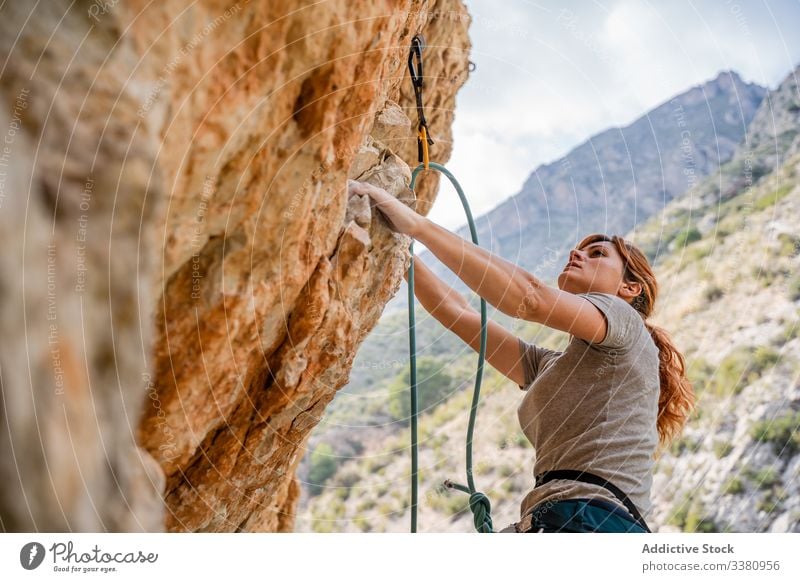 Active female climber ascending on cliff woman alpinist mountain practice climbing active mountaineering risk travel brave adventure courage altitude extreme