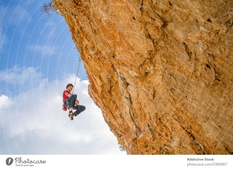 Courageous female climber hanging on cliff woman alpinist ascend mountain terrain adventure extreme risk challenge adrenalin freedom altitude rope journey sport