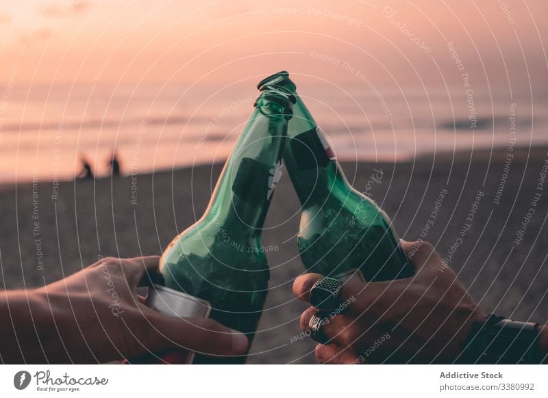 Friends toasting with beer on sunset beach bottle friend summer sea sky hand clink together relax enjoy drink alcohol beverage weekend evening vacation coast