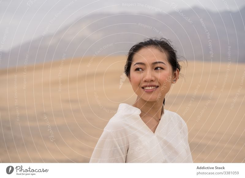 Cheerful young ethnic female tourist enjoying vacation in desert woman sandy explore tourism travel nature adventure dry traveler beauty freedom happy journey