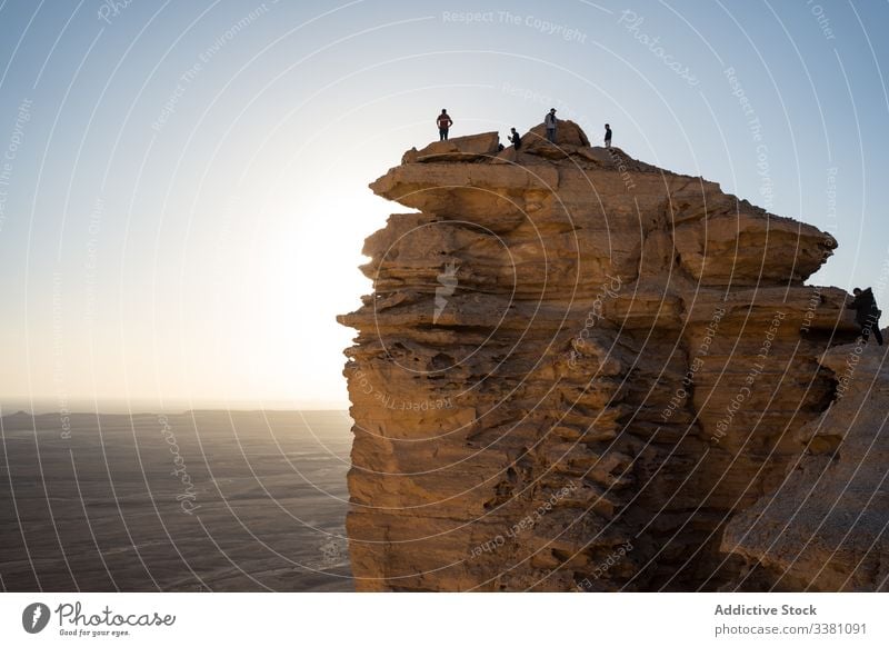 Unrecognizable tourists enjoying sunset on cliff group traveler contemplate sundown visit colorful nature freedom people adventure tourism sunrise destination