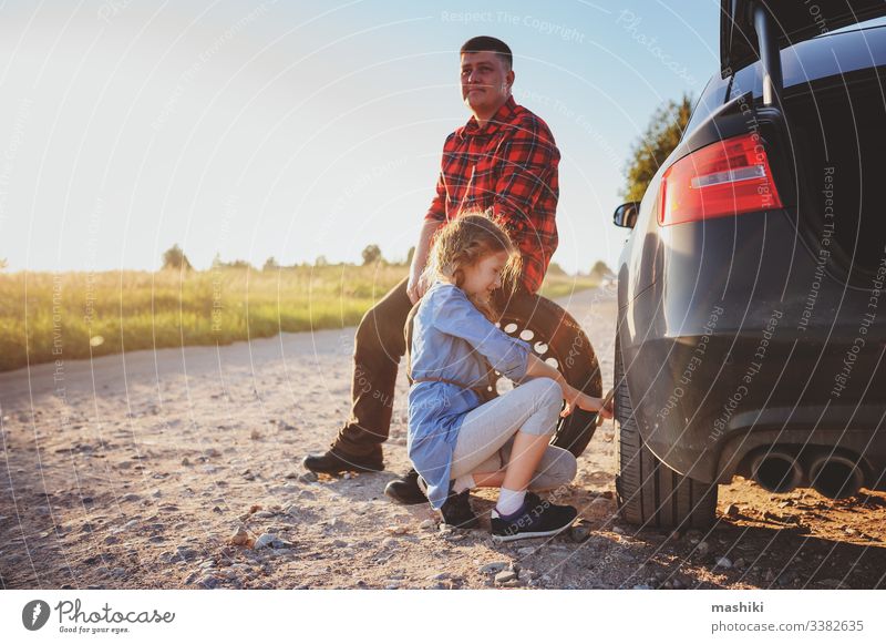 father and daughter changing broken tire during summer road trip car child family girl mechanic repair automobile man outdoors vehicle parent help dad fixing