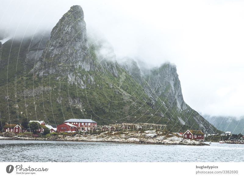 View from the sea to a fishing village with red houses (Rorbuer) on the Lofoten (Reine, Norway) Coast Lofotes cleaning Mountain Vacation in Norway Landscape