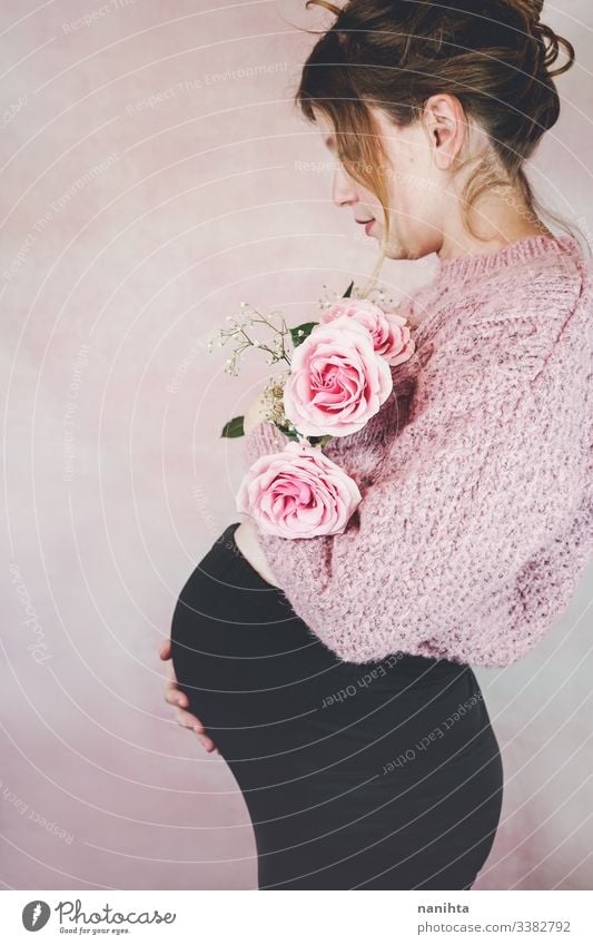 Young pregnant woman holding a bouquet of roses pregnancy mom waiting family love third trimester month weeks natural real candid real woman people flowers pink