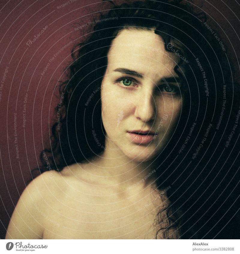 Analogue portrait of a young woman in front of a red wall Looking into the camera Central perspective Shallow depth of field Artificial light Day