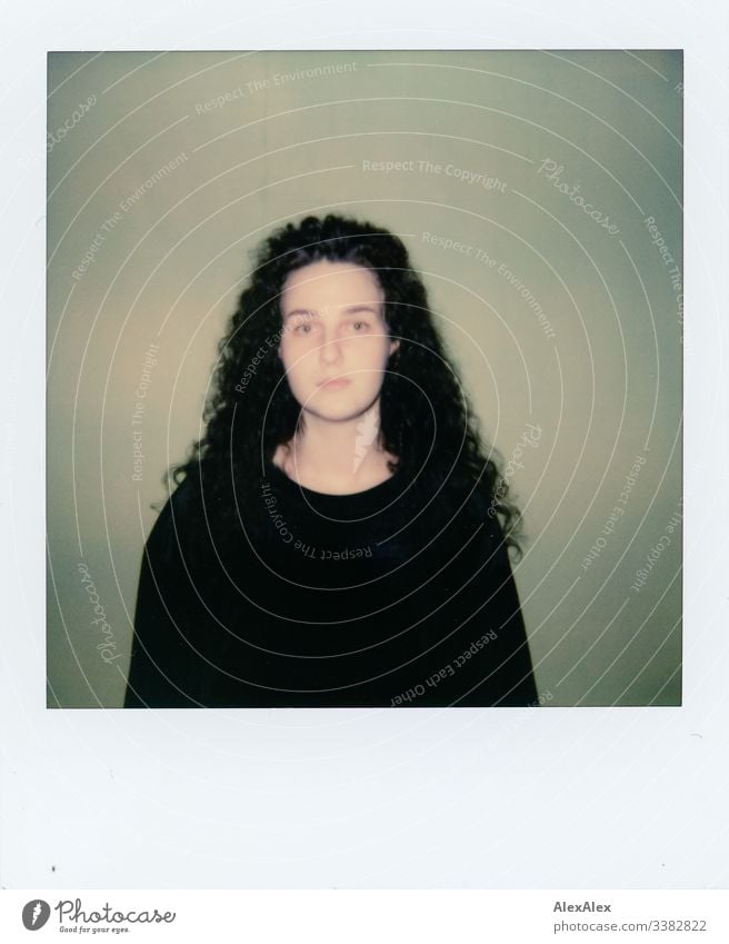 Analog Polaroid portrait of a young woman in front of a green wall Looking into the camera Central perspective Shallow depth of field Artificial light Day