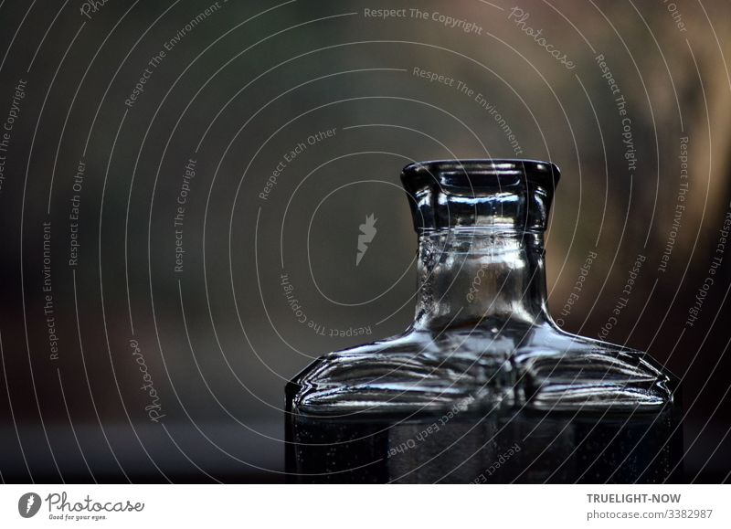 Neck of a square glass bottle that focuses and reflects daylight. Against a blurred background Glassbottle Reflection & Reflection," Close-up