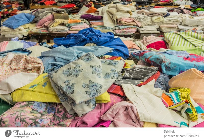 Rummage table and folded textiles in the background Bargain counter Textiles second hand Cloth Clothing Second-hand Second hand shop Muddled variegated Stack