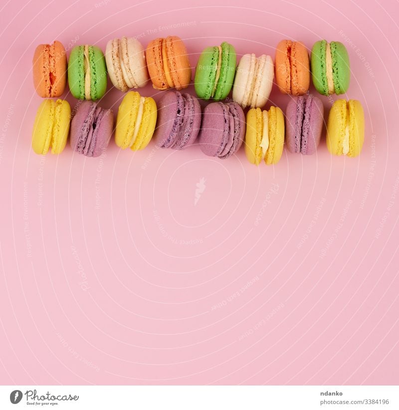 yellow, purple round baked macarons cakes on a pink background, dessert lies in a row macaroon meringue nobody pastry pile sandwich set snack stack sugar sweet